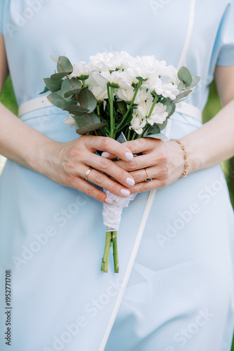 A bride in a blue dress holds a wedding bouquet