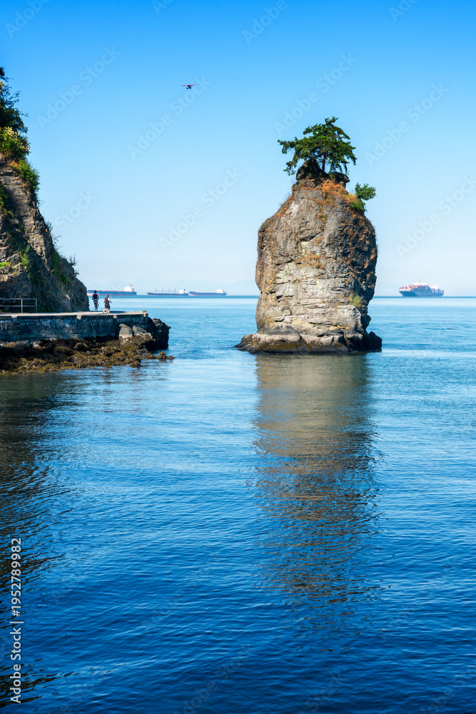 Fototapeta premium Siwash Rock Vancouver Seawall Sunshine vertical. Siwash Rock on the west side of Stanley Park in sunshine. Vancouver, British Columbia, Canada. 