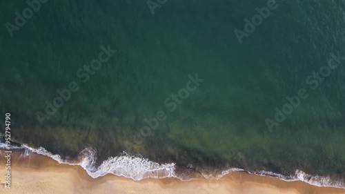 Aerial bird's eye view of golden sand beach meeting the turquoise ocean waves