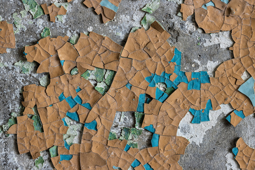 Peeling paint on the wall. Old concrete wall with cracked flaking paint. Weathered rough painted surface with patterns of cracks and peeling. Grunge texture for background and design. High resolution.