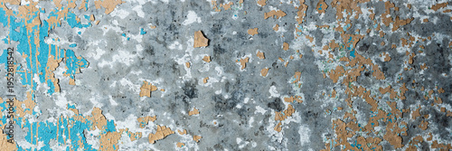 Peeling paint on the wall. Panorama of a concrete wall with old cracked flaking paint. Weathered rough painted surface with patterns of cracks and peeling. Wide panoramic grungy texture for background