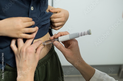 Photos Over-the-shoulder view of a physician injecting a patient in the stomach using a modern medical pen, focusing on the clinical interaction