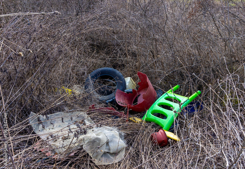 A pile of discarded household waste and litter dumped in a bush area, commonly known as fly tipping