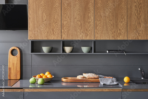The modern graphite-colored kitchen with
stone countertops and wooden doors is served with vegetables, fruits and bread