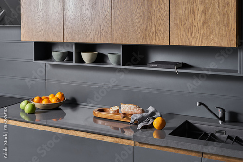 The modern graphite-colored kitchen with
stone countertops and wooden doors is served with vegetables, fruits and bread