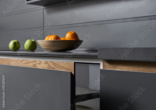 The modern graphite-colored kitchen with
stone countertops and wooden doors is served with vegetables, fruits and bread