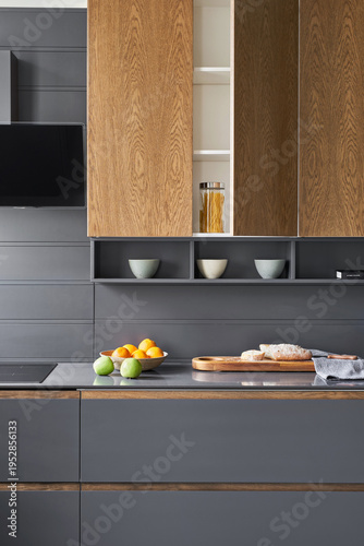 The modern graphite-colored kitchen with
stone countertops and wooden doors is served with vegetables, fruits and bread