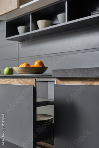 The modern graphite-colored kitchen with
stone countertops and wooden doors is served with vegetables, fruits and bread