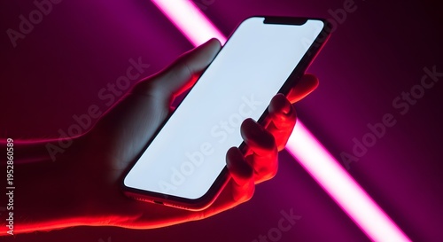 Hand holding smartphone with blank screen in neon lit room