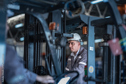 Bild auf Leinwand Caucasian male factory supervisor talking on radio with forklift driver in foreground