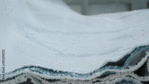 Industrial carpet manufacturing process showing stacks of finished rugs in a factory warehouse setting.