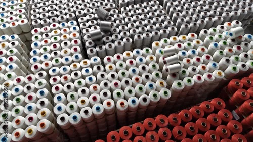 High angle view of organized stacks of colorful industrial yarn spools in a textile manufacturing factory warehouse.