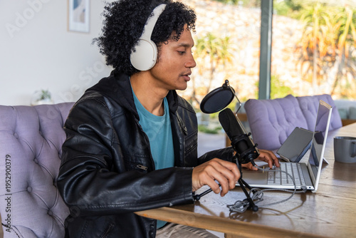 Photos African American man sitting at wooden table using silver laptop and speaking in
