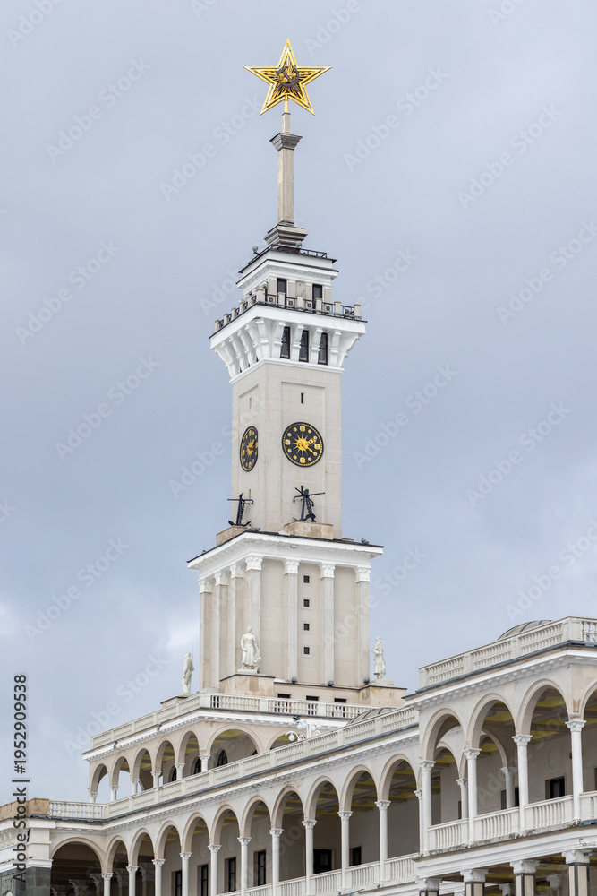 Fototapeta premium The North River Terminal or Rechnoy Vokzal of Moscow, Russia. Historic clock tower topped by a Soviet golden star rises above neoclassical arches and statues against a cloudy sky, it was built in 1937