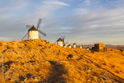 Consuegra windmills and castle illuminating at golden hour