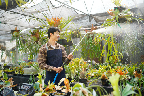 Foto A gardener with a watering hose and a sprayer water working in greenhouse and watering fern
