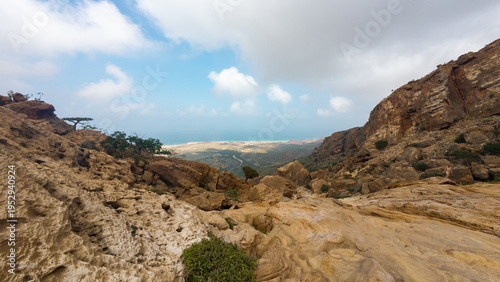 Rugged rocky canyon and distant valley under cloudy sky. Sokotra, Yemen.