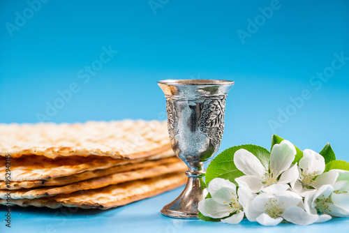 Happy passover. Metal goblet and traditional matzah on blue background.