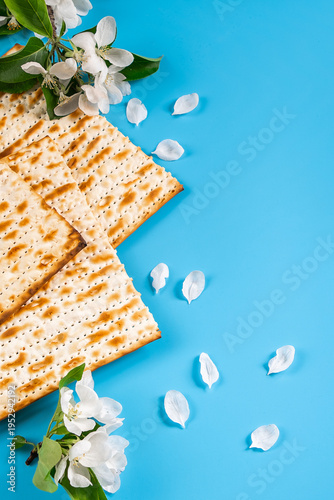 Holiday passover flatlay. Traditional matzah bread and spring flowers on blue background.