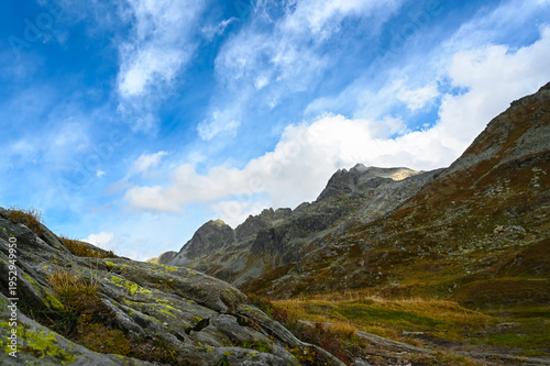 On the journey, a view from the Splügen Pass in the Alps, with the Via Spluga leading to the Surettahorn in Switzerland, featuring valleys, other peaks, and mountain panoramic scenery.