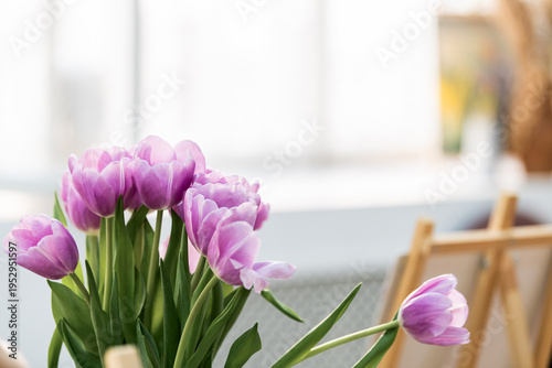Bouquet of purple tulips in vase near window. Spring floral arrangement in home interior.
