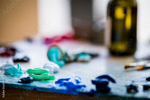 Artist palette with oil paint tube and brush. Colorful pigment spots on wooden board for oil painting.