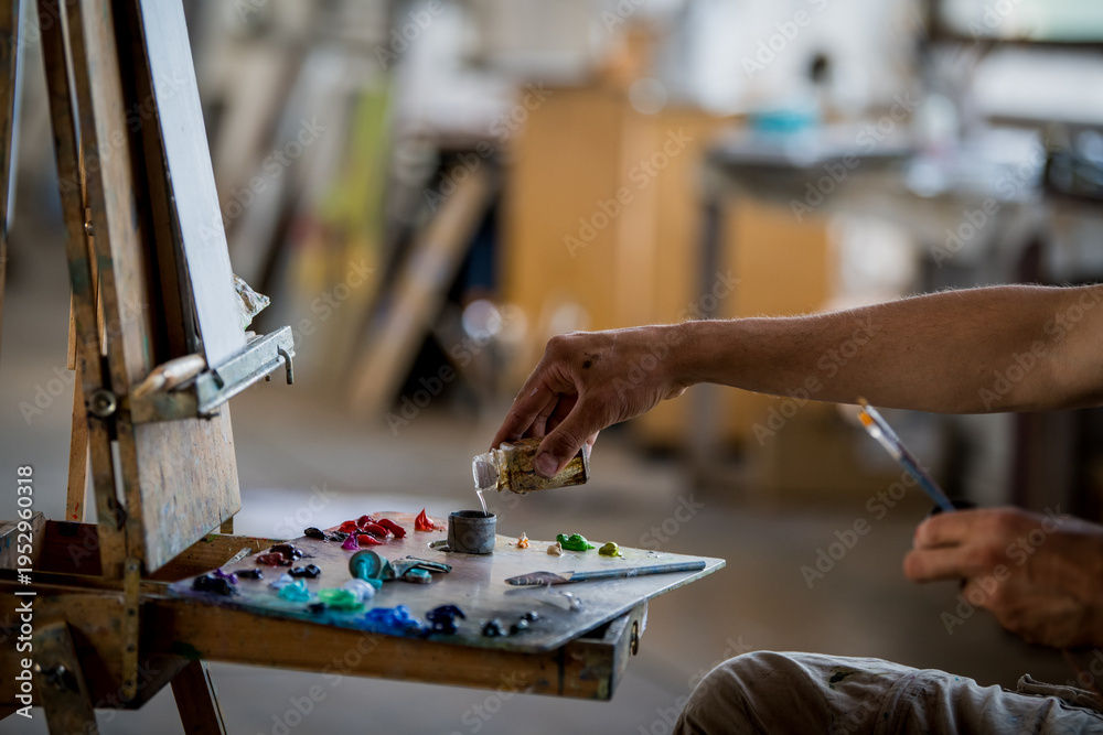 Fototapeta premium Man working in art studio mixing solvent for oil painting. Artist preparing canvas for creative project.