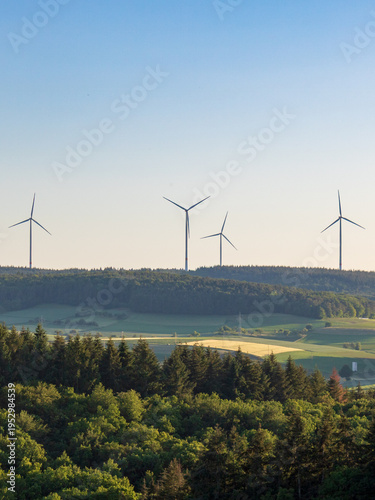 Wind turbines on hill above rural landscape, renewable energy in Germany