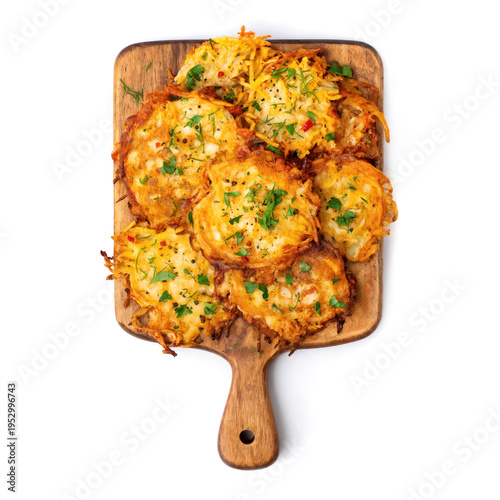 Crispy potato pancakes sit on a wooden board. They are golden and topped with herbs. These snacks show a tasty meal right after cooking in a hot pan.
