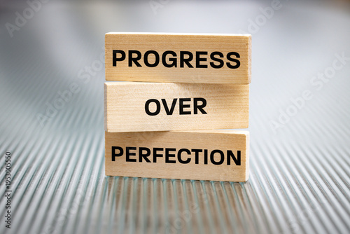 Progress beyond perfection. Sentence written on wooden tablets. Business concept. Motivating, supporting development. Close up. copy space