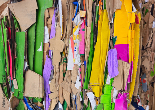 Vertical colored stack of waste  from pressed cardboard boxes, sorted and packed for recycling. Raw materials for the pulp industry. Garbage sorting secondary use of resources. Paper recycling photo