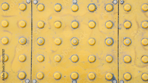 Foto Yellow tactile paving with raised truncated domes on a weathered sidewalk, servi