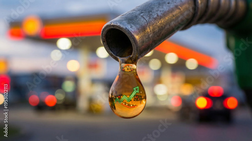 Fuel nozzle dripping gasoline with blurred gas station and rising graph reflected in droplet. Concept of rising fuel prices, oil market surge, energy costs increase, inflation, petroleum industry