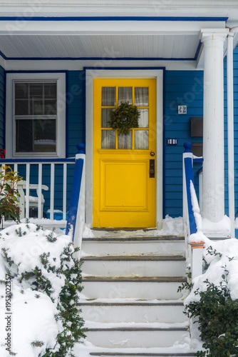 Fotografie vibrant yellow front door provides a striking contrast against blue siding durin