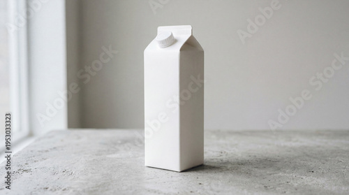 White milk carton stands on a table by the window in a simple indoor setting during the day
