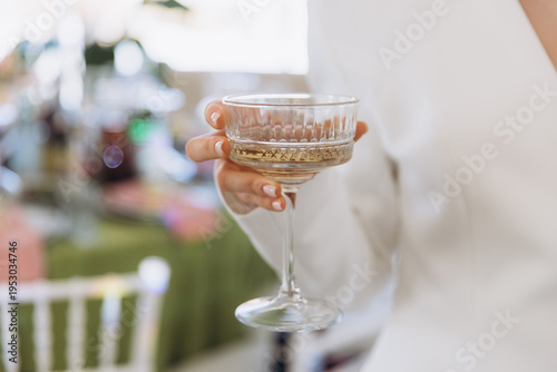 Woman holding champagne coupe glass, celebrating an event, enjoying a drink at a party, making a toast
