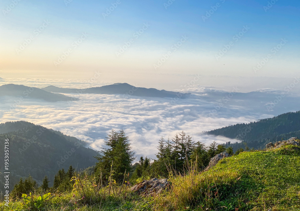 Fototapeta premium Breathtaking mountain landscape showing layers of hills emerging through morning mist and clouds