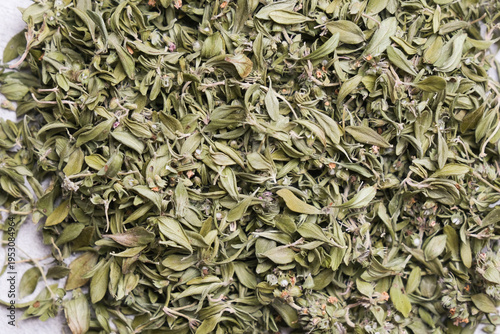 Dried organic thyme herb leaves scattered on a light surface, showcasing their green color and natural texture, ideal for culinary and herbal applications