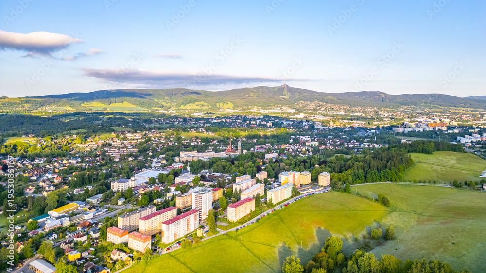 Fototapeta premium The town of Vratislavice nad Nisou in Czechia. It features buildings, green fields, and hills in the background. The scene captures a sunny day and the layout of the town.