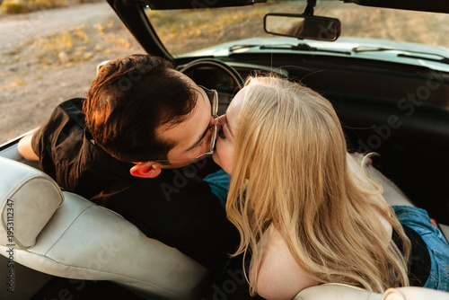 couple kissing in parked convertible car