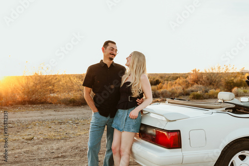young couple standing by car in the desert
