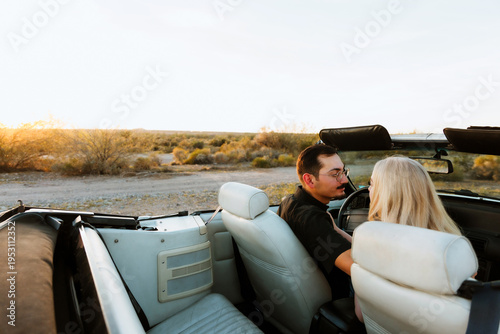 young couple looking at each other in convertible car