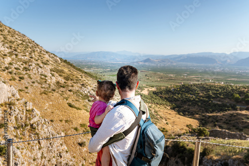 Father Holding Child While Admiring Mountain Landscape
