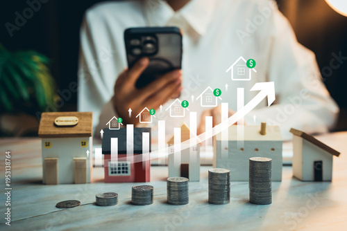 Real estate investment growth concept. Person using smartphone behind miniature houses and stacked coins with rising property value chart, housing market investment strategy