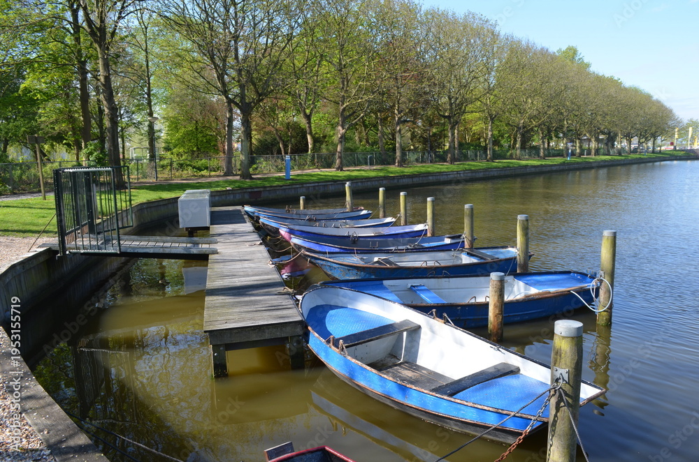 Obraz premium Blue rental rowing boats moored at canal dock, Netherlands