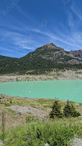 Vertical panning view of a stunning turquoise glacial lake with floating ice chunks.