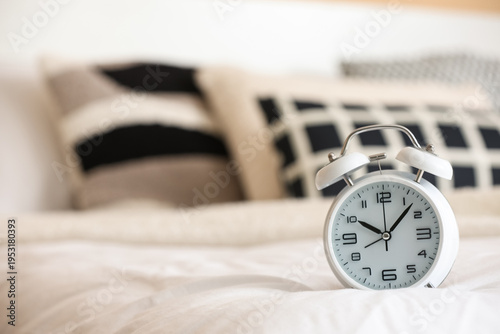 White alarm clock on bed, c...