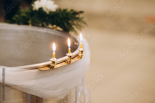 Fotografi Lit candles burning on christian baptismal font