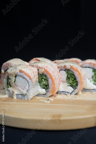 Sushi roll with salmon, cheese and avocado. Maki roll with shrimps fried, avocado and lattuce on a wooden plate . Delicious sushi rolls served on grey table