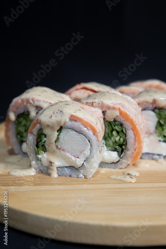 Sushi roll with salmon, cheese and avocado. Maki roll with shrimps fried, avocado and lattuce on a wooden plate . Delicious sushi rolls served on grey table